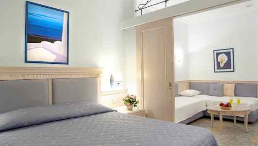 Et hotellrom med to senger og en sittegruppe, dekorert med blomster og malerier. (AI-generert tekst)