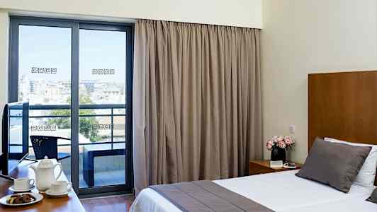 Et hotellrom med stor seng, kaffekopper på et bord og en balkong med utsikt. (AI-generert tekst)