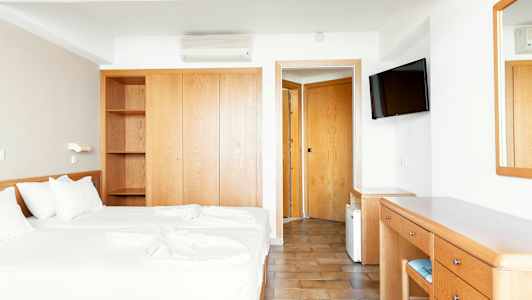 Hotellrom med to enkeltsenger, garderobe, skrivebord og speil. (AI-generert tekst)