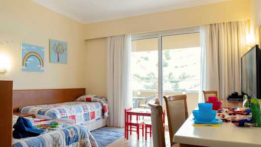 Et hotellrom med to enkeltsenger og et bord med stoler nær en balkong. (AI-generert tekst)