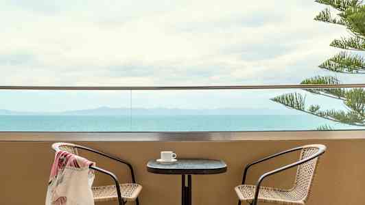 To stoler ved et bord på en terrasse med havutsikt. (AI-generert tekst)