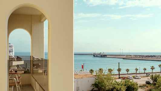 Utsikt mot havet med et cruiseskip og en ferge ved havnen, sett gjennom en bueformet åpning. (AI-generert tekst)