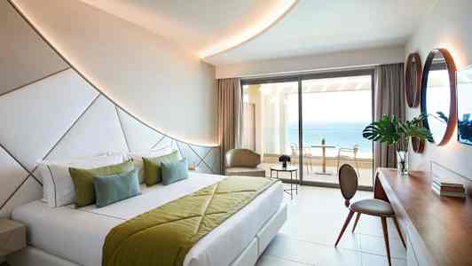 Moderne hotellrom med dobbeltseng og havutsikt fra balkongen. (AI-generert tekst)