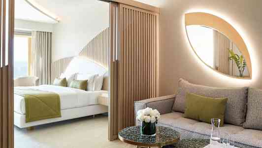 Moderne hotellrom med sofa og seng, dekorert med naturlige farger og treelementer. (AI-generert tekst)