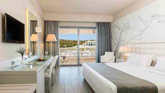 Et moderne hotellrom med en stor seng, skrivebord, TV og balkong med utsikt. (AI-generert tekst)