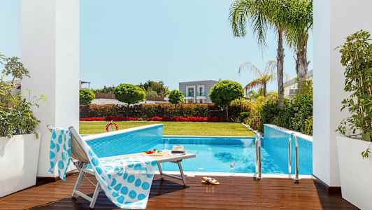 Utendørsbasseng omgitt av grøntområder og solsenger. (AI-generert tekst)