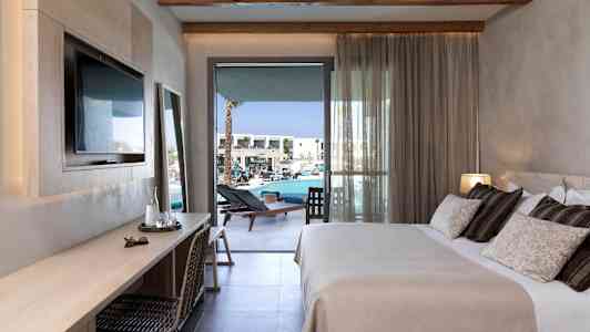 Et hotellrom med en dobbeltseng, skrivebord og balkong mot bassengområdet. (AI-generert tekst)