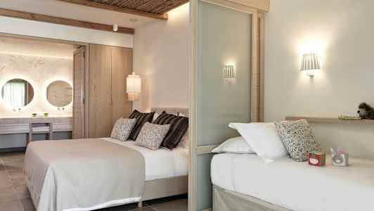 Et moderne hotellrom med to senger, dekorativ belysning og en synlig baderomsdel med to speil. (AI-generert tekst)