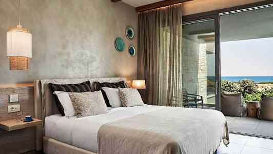 Et hotellrom med en seng og utsikt over havet. (AI-generert tekst)