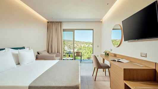 Et moderne hotellrom med dobbeltseng, skrivebord og stol, samt en balkong med utsikt over frodig terreng. (AI-generert tekst)