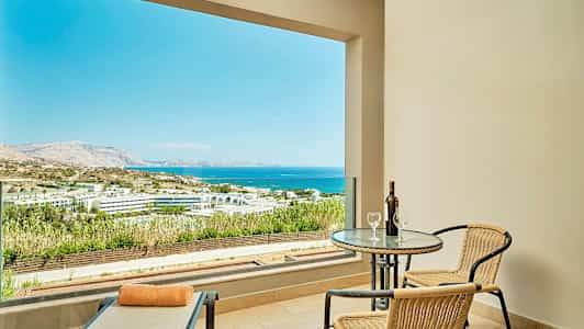 Terrasse med utsikt over havet og landskapet, bord med to stoler og en solseng. (AI-generert tekst)