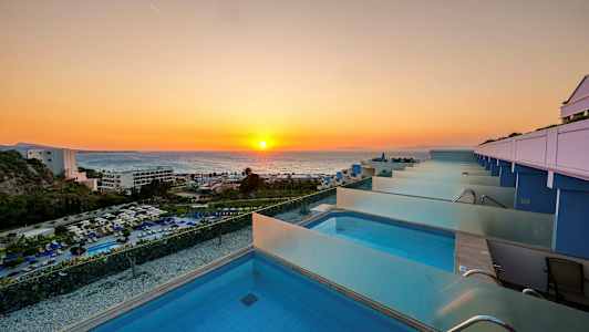 Utsikt over en rekke private bassenger med solnedgang over havet i bakgrunnen. (AI-generert tekst)