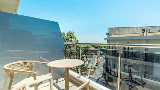 En balkong med bord og stoler i en bymiljø. (AI-generert tekst)