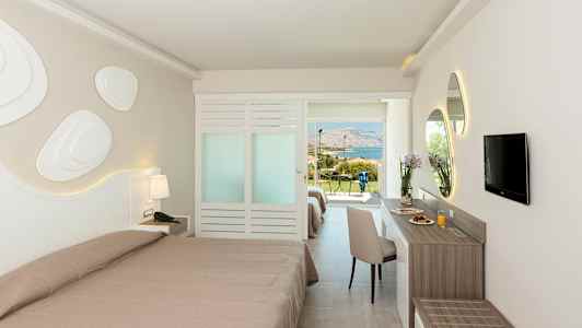 Hotellrom med to senger, skrivebord og TV. Utsikt mot grøntområder og havet. (AI-generert tekst)