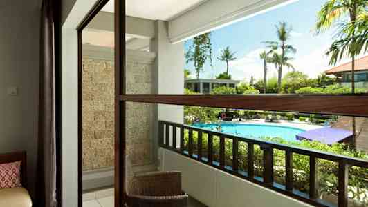 Balkong med utsikt over bassengområdet, med utemøbler og grøntområder. (AI-generert tekst)