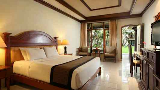 Et velmøblert hotellrom med en stor seng og en uteplass. (AI-generert tekst)