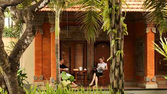 To personer sitter på en veranda til et hus dekorert i tradisjonell stil. (AI-generert tekst)