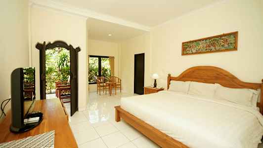 Et velutformet og lyst soverom med en stor seng, tredetaljer og sittegruppe nær vindu med utsikt mot grøntområder. (AI-generert tekst)