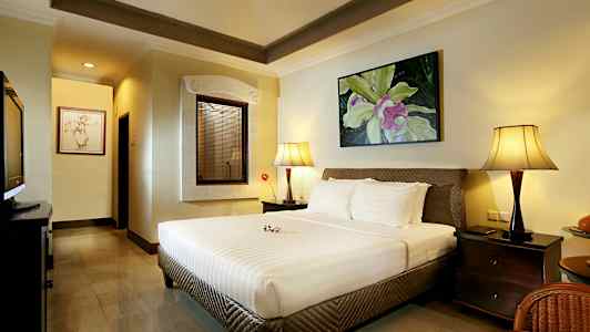 Et soverom med en stor seng, to nattbordslamper og et dekorativt bilde på veggen. (AI-generert tekst)