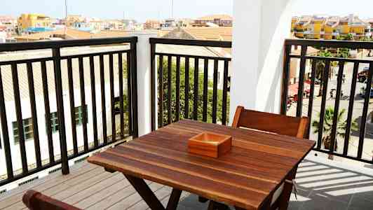 Utsikt fra en balkong med et trebord og stoler. (AI-generert tekst)