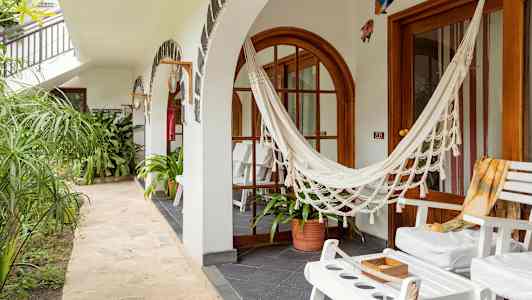 En uteplass med hvite stoler, en hengekøye og grønne planter. (AI-generert tekst)