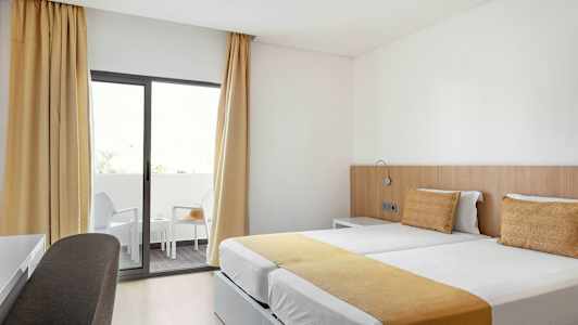 Hotellrom med to enkeltsenger og balkong. (AI-generert tekst)