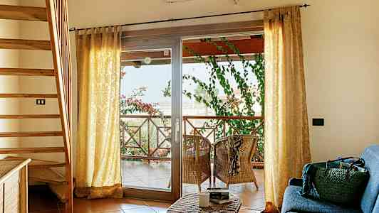 Interiør med trapp, sofakrok og terrasse med sitteplasser og grønne planter. (AI-generert tekst)