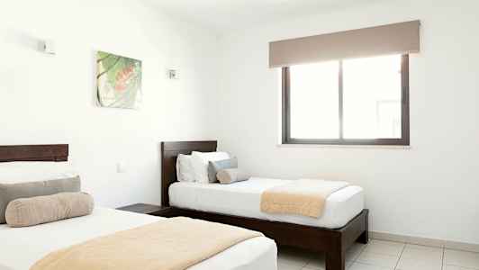 To enkeltsenger i et lyst soverom med et vindu og en veggdekorasjon. (AI-generert tekst)