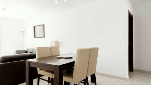 Et moderne innredet stue med spisebord og stoler i forgrunnen. (AI-generert tekst)