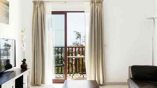 Et rom med sittegruppe, en TV og en balkong med utsikt. (AI-generert tekst)