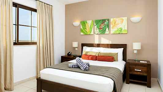 Et moderne hotellrom med en dobbeltseng, nattbord og dekorativ veggkunst. (AI-generert tekst)