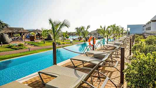 Solstoler ved et basseng omgitt av palmer. (AI-generert tekst)