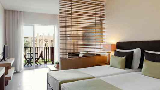 Hotellrom med to enkeltsenger, en sitteplass med en avdeler og en terrasse med utsikt. (AI-generert tekst)