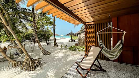 Terrasse med hengekøye og solseng, utsikt over sandstrand og palmer. (AI-generert tekst)