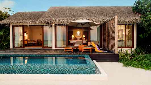 En strandvilla med privat basseng og sittemøbler på en terrasse av tre. (AI-generert tekst)