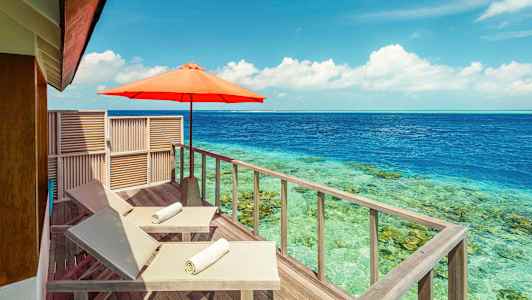 To solsenger med hvite håndklær på en treterrasse ved havet, med en parasoll. (AI-generert tekst)