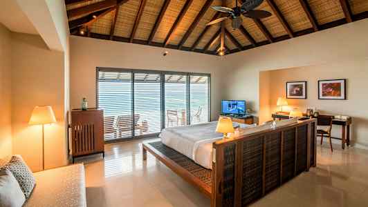 Interiør av et soverom med en dobbeltseng og et åpent vindu mot en balkong. (AI-generert tekst)