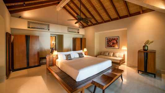 Et soverom med en stor seng, tremøbler og høyt tak. (AI-generert tekst)