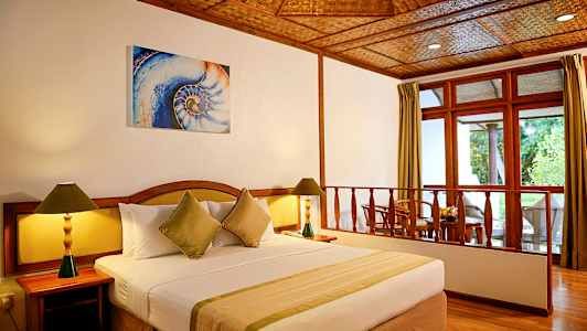 Et hotellrom med en stor seng, to nattbord med lamper og en sittegruppe ved vinduet. (AI-generert tekst)