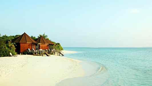 Bungalower ved en sandstrand med klart vann. (AI-generert tekst)