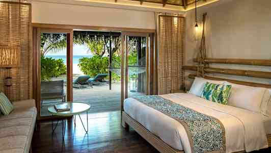 Et soverom med en dobbeltseng og tropisk dekor, samt utgang til en terrasse med havutsikt. (AI-generert tekst)