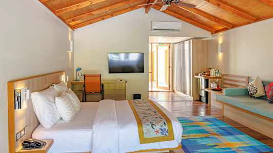 Et lyst innredet hotellrom med en dobbeltseng, en flatskjerm-TV og sittemøbler. (AI-generert tekst)