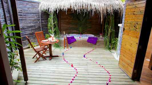 En utendørsterrasse med bord, stoler, boblebad og dekorasjoner. (AI-generert tekst)