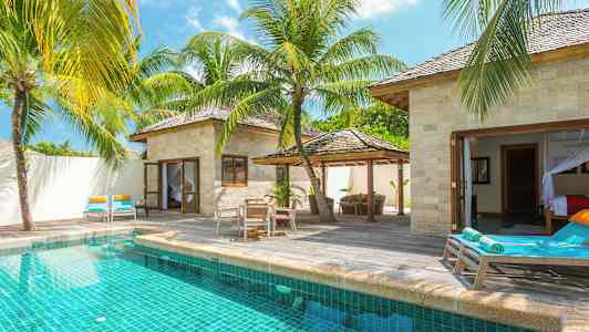 En villa med eget basseng, omgitt av solsenger og tropiske palmer. (AI-generert tekst)