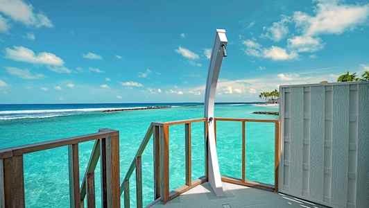 En dusj på en terrasse med utsikt over turkist hav under en klar himmel. (AI-generert tekst)