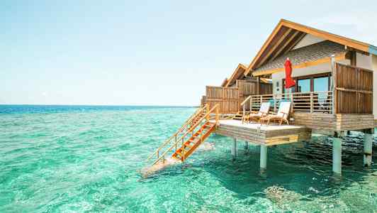 Fotografi av en bungalow på påler over turkist vann. (AI-generert tekst)