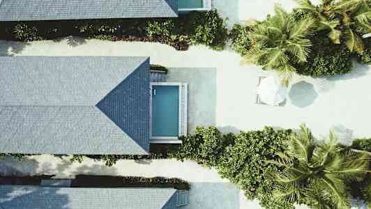 Luftfoto av feriehytter med små bassenger og vegetasjon. (AI-generert tekst)