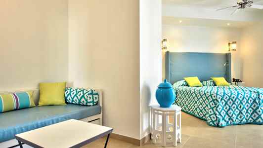 Et hotellrom med seng, lys dekor og dekorative puter. (AI-generert tekst)