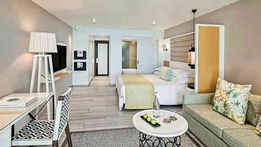 Et hotellrom med moderne innredning, seng, skrivebord, sofa og et kaffebord. (AI-generert tekst)