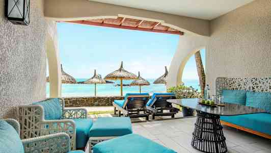 En terrasse med blå sittemøbler og utsikt mot havet med parasoller. (AI-generert tekst)